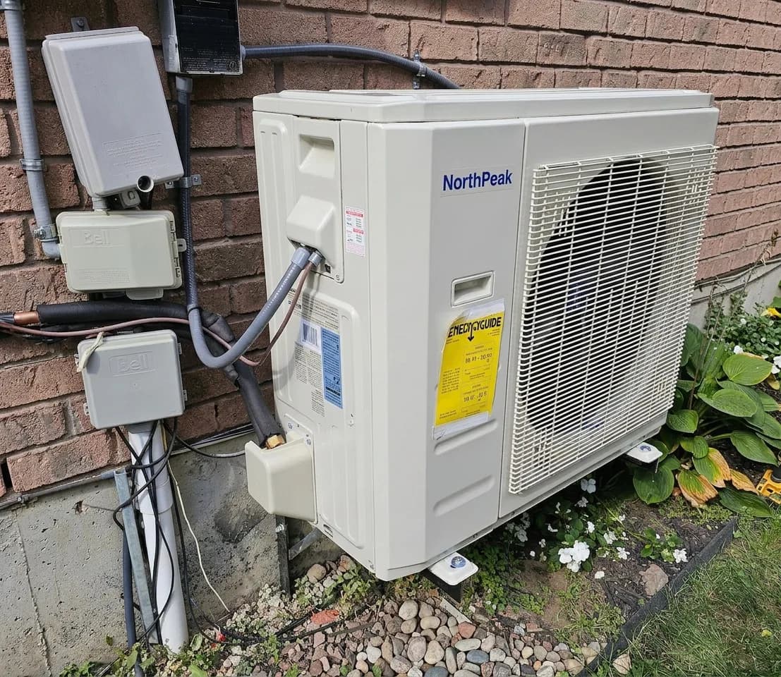 Outdoor mini-split condenser on a residential patio against brick siding.