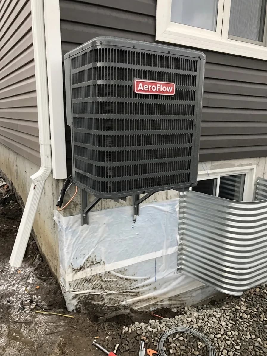 Outdoor AC condenser installed against modern dark siding.