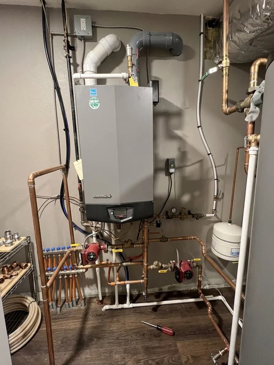 Tankless boiler installation with neatly routed copper supply lines and PVC venting.